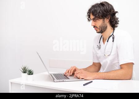 giovane medico con stetoscopio utilizzando computer portatile conversazione videoconferenza chiamata con il paziente alla scrivania in clinica sanitaria. Consulenza e assistenza sanitaria Foto Stock