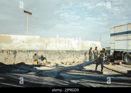 Pescatori che riparano reti, Port de Peche traditionelle, Nouadhibou, Mauritania Foto Stock