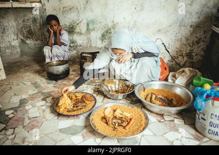 Ebeti Abidino, figlia del pescatore ben Abden che prepara cibo per la famiglia, riso con pesce, il piatto tradizionale dei pescatori e. Foto Stock