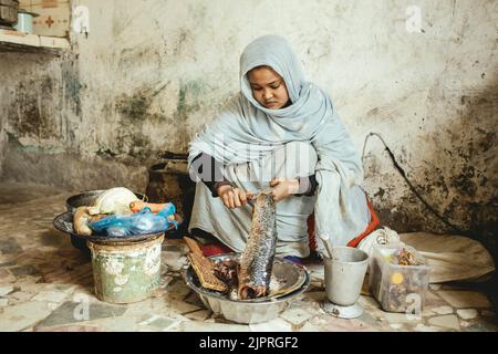 Ebeti Abidino, figlia del pescatore ben Abden che prepara cibo per la famiglia, riso con pesce, il piatto tradizionale dei pescatori e. Foto Stock