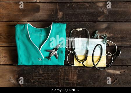 Un'uniforme medica e una maschera accanto a uno stetoscopio su un tavolo intorno a soldati di plastica sparsi, fermare la guerra in Ucraina, medicina militare 2022 Foto Stock