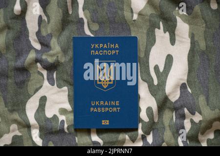 Il passaporto ucraino straniero biometrico si trova su un mimetizzazione sfondo verde militare, la guerra in Ucraina, la protezione militare dei paesi Foto Stock