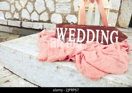 Bella decorazione di nozze su scale di pietra con freccia di legno matrimonio. Grandi lanterne di candela con fiori rosa e nastri su tessuto rosa polveroso outsid Foto Stock