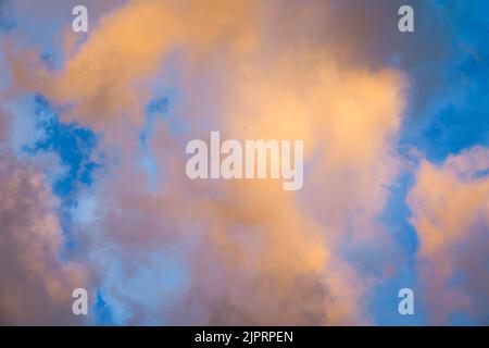 Cielo blu con nuvole colorate color giallo pastello, arancione, rosa, lilla, viola durante l'alba crepuscolo per lo sfondo. Foto Stock