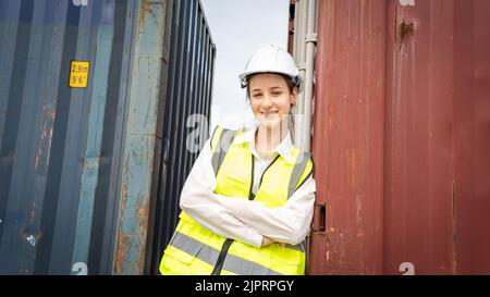 Donna capocorda sorridere a fianco del contenitore Cargo in magazzino , Manager in caschetto bianco Safety Supervisor in Container Custom Terminal Port Concept impo Foto Stock