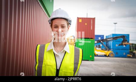 Donna capocorda sorridere a fianco del contenitore Cargo in magazzino , Manager in caschetto bianco Safety Supervisor in Container Custom Terminal Port Concept impo Foto Stock