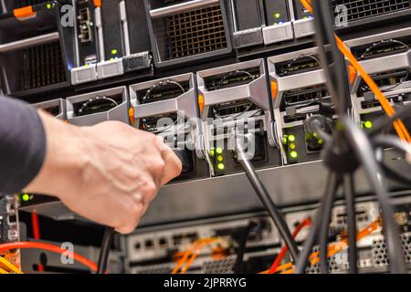 Primo piano del tecnico maschio che collega il cavo del computer in SAN Foto Stock