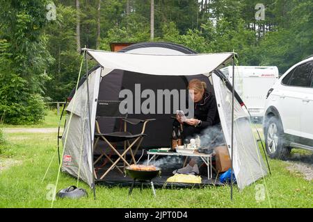 La giovane donna siede su una tenda durante il viaggio in campeggio. Foto Stock