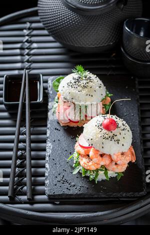Delizioso e squisito hamburger di sushi con verdure e frutti di mare su piatto di strone. Dessert giapponese a base di pesce e riso. Foto Stock