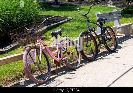 Ocean Beach, New York, USA - 30 maggio 2022: Due vecchie biciclette arrugginite appoggiate contro una recinzione nell'Ocean Beach Village di Fire Island contro un cartello rea Foto Stock