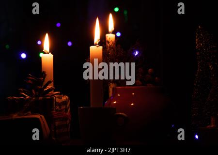 Un tavolo con i regali di Capodanno, smalti e candele, hanno portato un piccolo albero decorativo di Natale nel buio, felice anno nuovo Foto Stock