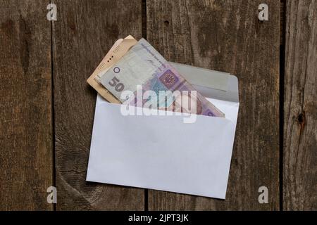 Denaro ucraino 50 hryvnia in una busta bianca, finanza e stipendio in una busta, un regalo in denaro Foto Stock