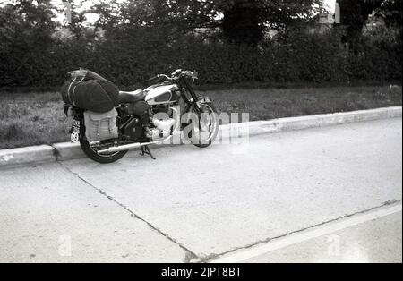 1950s, storico, parcheggiato su una strada, una moto BSA dell'epoca. Sul retro della moto, una custodia in stoffa impaccata sulle mutandine in tela pronta per una vacanza in giro per l'Europa. Foto Stock