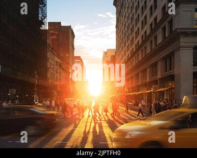Folle di persone e auto nel trafficato incrocio sulla 23rd Street e 5th Avenue a New York City con il tramonto splendente sullo sfondo Foto Stock