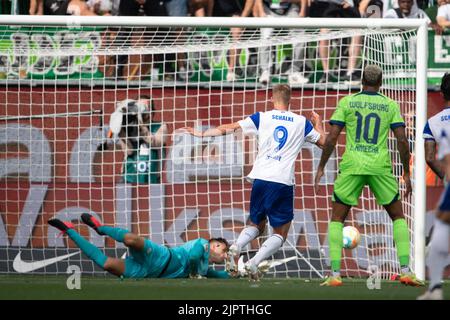 Wolfsburg, Germania. 20th ago, 2022. Calcio: Bundesliga, VfL Wolfsburg - FC Schalke 04, Giornata 3, Volkswagen Arena. Il portiere di Wolfsburg Koen Casteels (l) ferma un calcio di punizione da Simon Terodde (m) di Schalke. Credit: Swen Pförtner/dpa - NOTA IMPORTANTE: In conformità ai requisiti della DFL Deutsche Fußball Liga e del DFB Deutscher Fußball-Bund, è vietato utilizzare o utilizzare fotografie scattate nello stadio e/o della partita sotto forma di sequenze di immagini e/o serie di foto simili a video./dpa/Alamy Live News Foto Stock