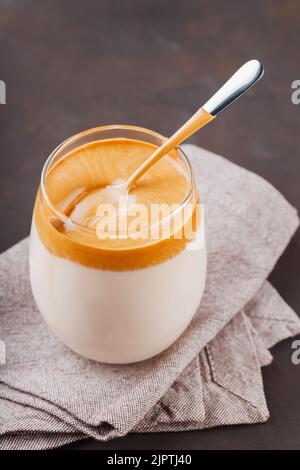 Caffè Dalgona fatto in casa su sfondo scuro. Dalgona caffè schiumoso con un cucchiaio su un tovagliolo di lino. Bevanda sudcoreana con caffè istantaneo montato, su Foto Stock