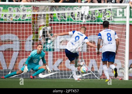 Wolfsburg, Germania. 20th ago, 2022. Calcio: Bundesliga, VfL Wolfsburg - FC Schalke 04, Giornata 3, Volkswagen Arena. Simon Terodde (centro) di Schalke tira un calcio di punizione. Il portiere di Wolfsburg Koen Casteels si tuffa a sinistra. Credit: Swen Pförtner/dpa - NOTA IMPORTANTE: In conformità ai requisiti della DFL Deutsche Fußball Liga e del DFB Deutscher Fußball-Bund, è vietato utilizzare o utilizzare fotografie scattate nello stadio e/o della partita sotto forma di sequenze di immagini e/o serie di foto simili a video./dpa/Alamy Live News Foto Stock