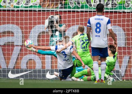 Wolfsburg, Germania. 20th ago, 2022. Calcio: Bundesliga, VfL Wolfsburg - FC Schalke 04, Giornata 3, Volkswagen Arena. Il portiere di Wolfsburg Koen Casteels tiene un calcio di punizione da Simon Terodde di Schalke. Credit: Swen Pförtner/dpa - NOTA IMPORTANTE: In conformità ai requisiti della DFL Deutsche Fußball Liga e del DFB Deutscher Fußball-Bund, è vietato utilizzare o utilizzare fotografie scattate nello stadio e/o della partita sotto forma di sequenze di immagini e/o serie di foto simili a video./dpa/Alamy Live News Foto Stock