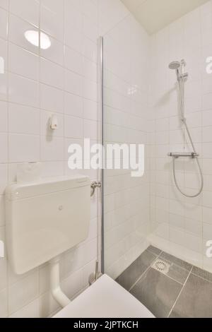 Lavandino base armadio e specchio in bagno piastrellato bianco con WC appeso a parete Foto Stock