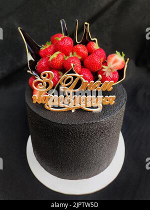 Elegante torta nera con vaso e fragole Foto Stock