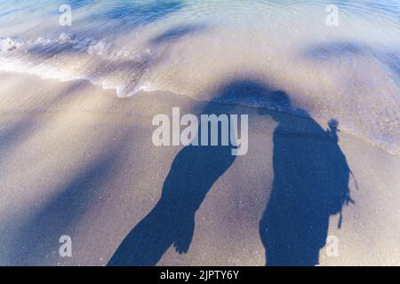 L'ombra di due persone sulla riva del mare Foto Stock