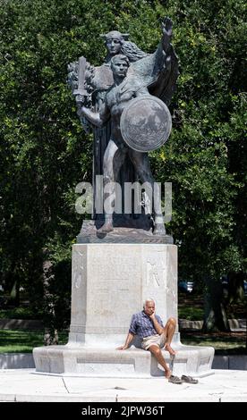 Charleston, SC - Agosto 7 2022: Un vecchio uomo maschio rilassante a piedi nudi sul confederato difensori di Charleston Memorial Foto Stock