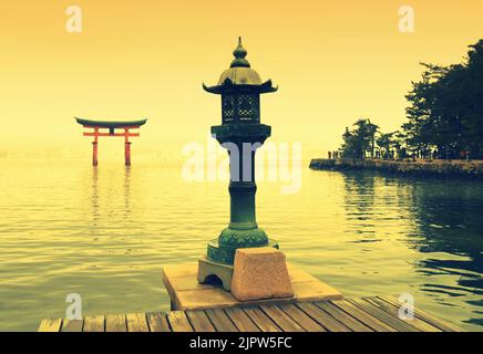 Lanterna di bronzo e porta torii sull'isola di Miyajima, Itsukushima, città di Hatsukaichi, prefettura di Hiroshima, Giappone Foto Stock