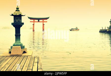 Lanterna di bronzo e porta torii sull'isola di Miyajima, Itsukushima, città di Hatsukaichi, prefettura di Hiroshima, Giappone Foto Stock