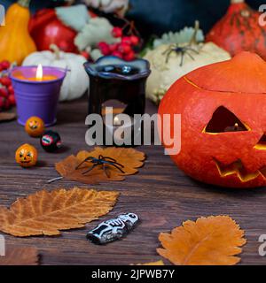 Zucche di Halloween su un tavolo di legno scuro con ragni, candele, zucche, foglie su sfondo sfocato. Messa a fuoco selettiva. Concetto di Halloween. Foto Stock