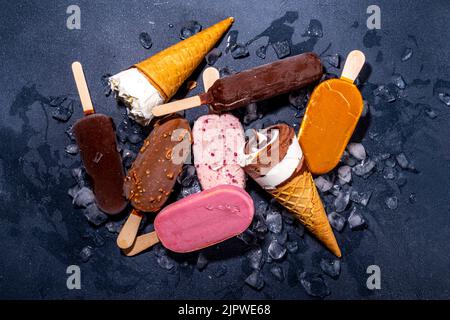 Set di vari gelati su sfondo nero. Assortimento di coni e popsicles di icecream su sfondo scuro vista dall'alto piano copia spazio Foto Stock