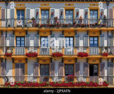 San Sebastian, Spagna - 26 giugno 2021: Facciate di case ornate e balconi in metallo con fiori in Piazza della Costituzione nel centro storico di Donostia Paesi Baschi Foto Stock