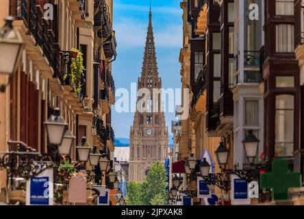 Vista lungo una strada nella città vecchia su buon Pastore di San Sebastian cattedrale in rinascita gotica con una guglia di 75 m a Donostia, Paesi Baschi, Spagna Foto Stock