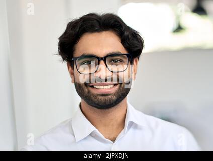Giovane uomo d'affari indiano sorridente che indossa occhiali, ritratto alla testa. Foto Stock