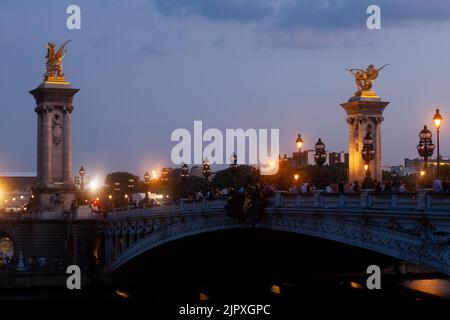 Ponte di Pont Alexandre III e lampioni illuminati al tramonto. 7th Arrondissement, Parigi, Francia Foto Stock