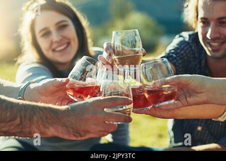 Lasciate che i bei momenti rotolino. Un gruppo di amici brinda con le loro bevande all'aperto. Foto Stock