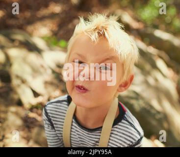 Che cosa è il volto più divertente che si può tirare. Ritratto di un adorabile ragazzino che gioca all'aperto. Foto Stock