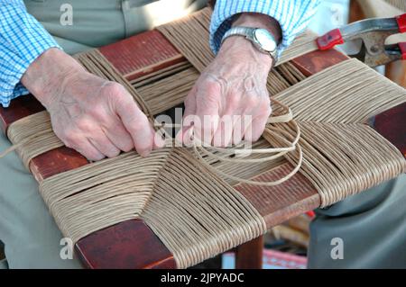 Le mani che lavorano ad una mostra di arte e artigianato facendo artigianato e tessitura d'arte per la vendita Foto Stock