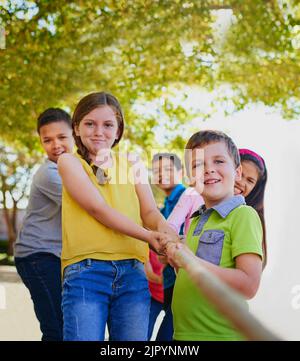 Insieme siamo molto più forti: Un gruppo eterogeneo di bambini che giocano fuori una guerra. Foto Stock