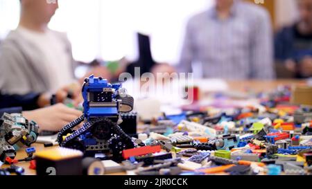 sul tavolo sono sparsi molti dettagli dal designer dei bambini, cubi, fili, tavole, ruote, piccoli robot multicolore, macchine. i bambini amano la robotica, la programmazione, la modellazione. Foto di alta qualità Foto Stock