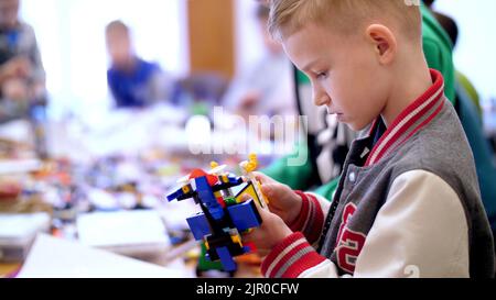 il ragazzo di 10 anni, gioca nel designer da cubi, piastre, circuiti, fili. un piccolo inventore crea robot, macchine da diverse parti del designer. Foto di alta qualità Foto Stock