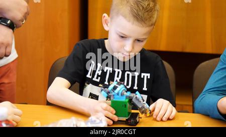 il ragazzo di 9 anni, gioca nel designer da cubi, piastre, circuiti, fili. un piccolo inventore crea robot, macchine da diverse parti del designer. Foto di alta qualità Foto Stock