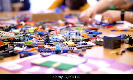 sul tavolo sono sparsi molti dettagli dal designer dei bambini, cubi, fili, tavole, ruote, piccoli robot multicolore, macchine. i bambini amano la robotica, la programmazione, la modellazione. Foto di alta qualità Foto Stock