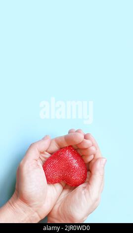 Cuore rosso nella donna mani su sfondo azzurro. Vista dall'alto di Flat Lay. Copia spazio per il testo. Foto Stock
