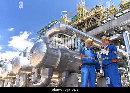 lavoro di squadra: gruppo di lavoratori industriali in una raffineria - macchine e attrezzature per la lavorazione del petrolio Foto Stock