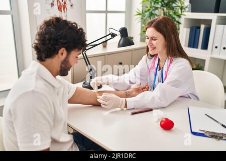 L'uomo e la donna che indossano l'uniforme del medico che hanno analisi del sangue in clinica Foto Stock