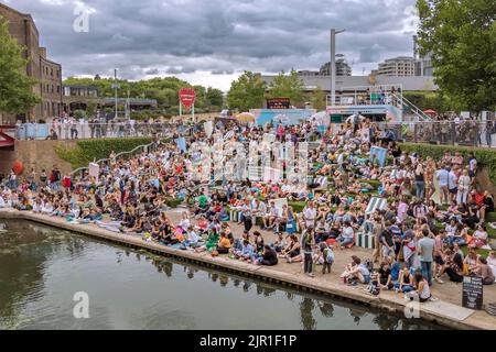 Folle di persone che si siedono sui gradini del canale del Regent vicino a Granary Square a Kings Cross in una calda serata estiva a Londra Foto Stock