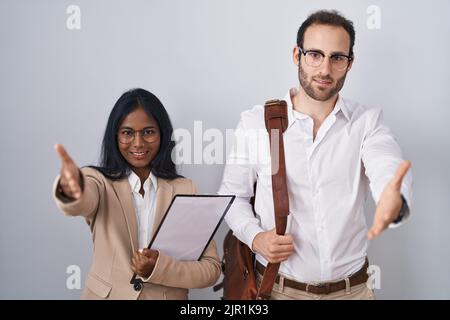 Interracial business coppia indossando occhiali sorridenti amichevole offrendo handshake come saluto e accogliente. Business di successo. Foto Stock