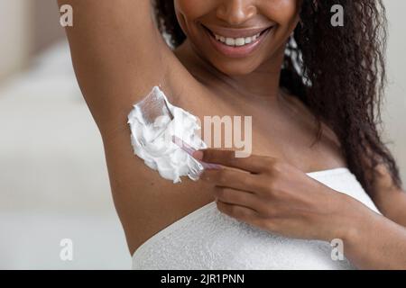 Concetto di depilazione. Donna nera Rimozione dei capelli dell'ascella con Razor e schiuma da barba Foto Stock