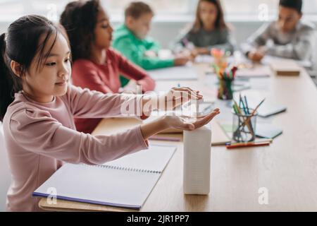 Giapponese Schoolgirl disinfezione delle mani durante la lezione a scuola Foto Stock