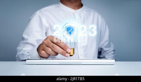 Numeri di anno di calendario 2023 brillanti, stile neon con sicurezza informatica, icona dello scudo in lampadina di tendenza creativa tenuta da uomo d'affari con tastiera comp Foto Stock